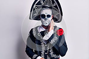 Young man wearing mexican day of the dead costume over white touching mouth with hand with painful expression because of toothache