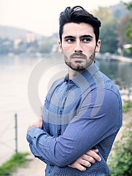 Young man wearing beside picturesque river or lake