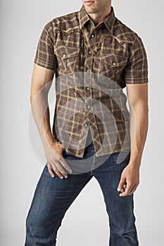 Young man wearing plaid western wear shirt and denim jeans. Men`s trendy casual clothing fashions styles.