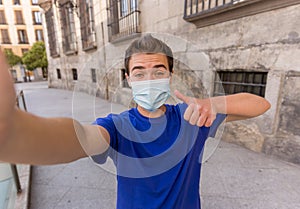 Young man wearing protective face mask video calling friends in the New Normal