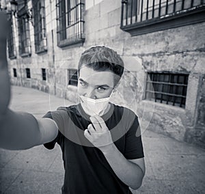 Young man wearing protective face mask video calling friends in the New Normal