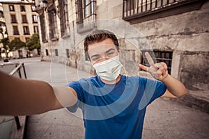 Young man wearing protective face mask video calling friends in the New Normal