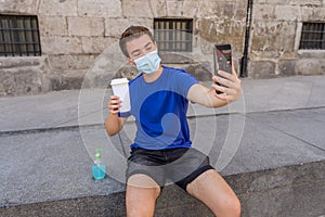 Young man wearing protective mask using hand sanitizer and video calling friends in the New Normal