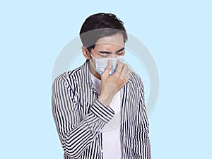 Young man wearing  protective medical mask, pinched his nose and sneezed