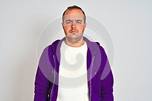 Young man wearing purple sweatshirt standing over isolated white background depressed and worry for distress, crying angry and