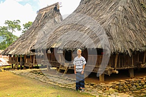 a young man wearing sarong with traditional houses on the backround in Wologai Village East Nusa Tenggara