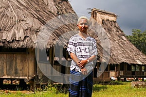 a young man wearing sarong with traditional houses on the backround in Wologai Village East Nusa Tenggara