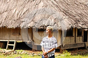 a young man wearing sarong with traditional houses on the backround in Wologai Village East Nusa Tenggara