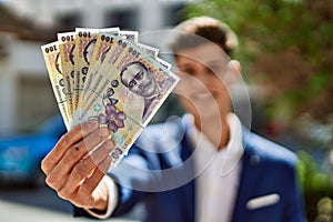 Young man wearing suit holding romania lei banknotes at street