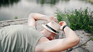 Young man is wearing summer shorts, straw hat and sunglasses, is relaxing on a beach