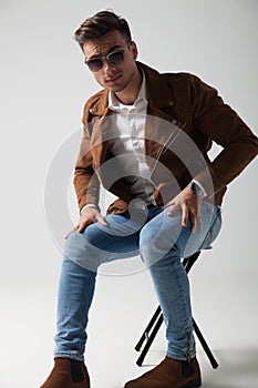 Young man wearing sunglasses and leather jacket sitting