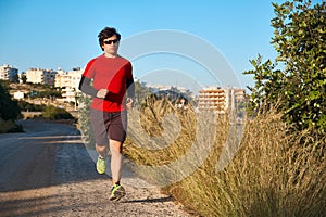 Young man wearing sunglasses on a morning jog in the countryside