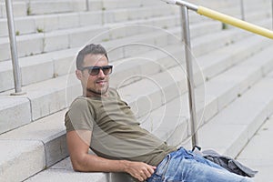 Young man wearing sunglasses sitting on stairs