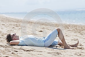 Young man wearing sunglasses while sunbathing at the beach