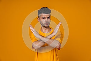 Young man wearing t-shirt looking strictly and gesturing stop sign