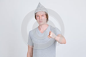 Young man wearing tin foil hat as conspiracy theory concept pointing at camera