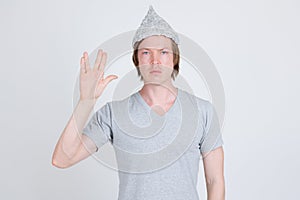 Young man wearing tin foil hat as conspiracy theory concept showing Vulcan salute in Star Trek