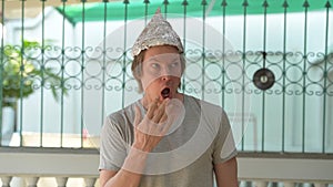 Young man wearing tin foil hat and looking shocked outdoors