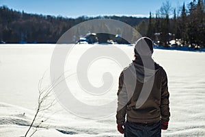 Young man wearing a tuque is contemplating the horizon