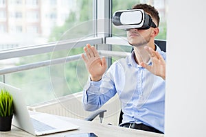 Young man wearing virtual reality glasses in modern interior design coworking studio.