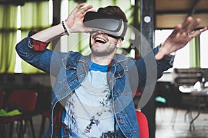 Young man wearing virtual reality glasses in modern interior design coworking studio. Smartphone using with VR goggles