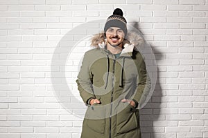 Young man wearing warm clothes against wall. Ready for winter vacation