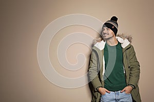 Young man wearing warm clothes on color background, space for text. Ready for vacation