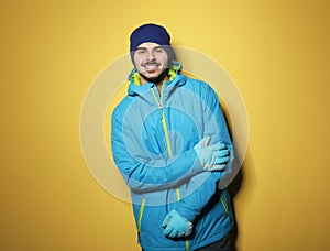 Young man wearing warm clothes on color background, space for text. Ready for winter