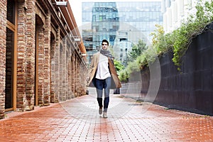 Young man wearing winter clothes in the street. Young guy with modern hairstyle with coat, blue jeans and white sweeter photo