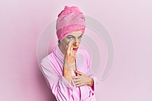 Young man wearing woman make up wearing shower towel on head and bathrobe pointing to the eye watching you gesture, suspicious