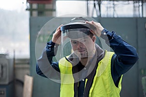 Young man welder with Down syndrome working in industrial factory, social integration concept.