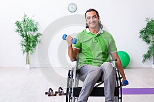 Young man in wheel-chair doing exercises indoors