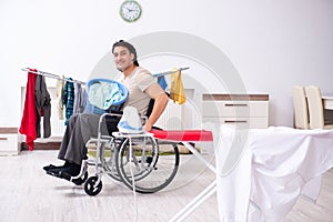 The young man in wheel-chair doing ironing at home