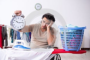 The young man in wheel-chair doing ironing at home