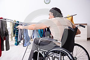 The young man in wheel-chair doing ironing at home