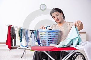 Young man in wheel-chair doing ironing at home