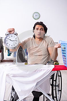 Young man in wheel-chair doing ironing at home