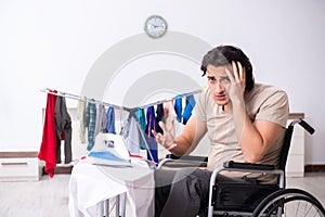 Young man in wheel-chair doing ironing at home