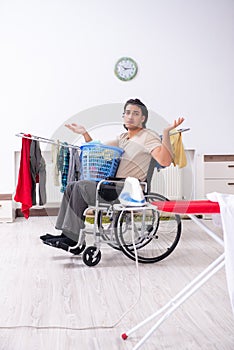 Young man in wheel-chair doing ironing at home