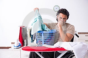 Young man in wheel-chair doing ironing at home