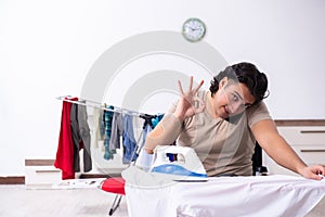 Young man in wheel-chair doing ironing at home