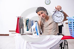 Young man in wheel-chair doing ironing at home