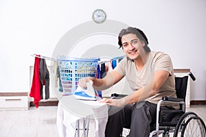 Young man in wheel-chair doing ironing at home