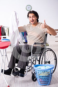 Young man in wheel-chair doing ironing at home