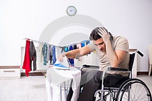 Young man in wheel-chair doing ironing at home