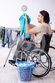 Young man in wheel-chair doing ironing at home