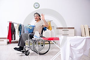 Young man in wheel-chair doing ironing at home