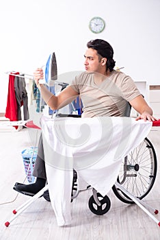 Young man in wheel-chair doing ironing at home