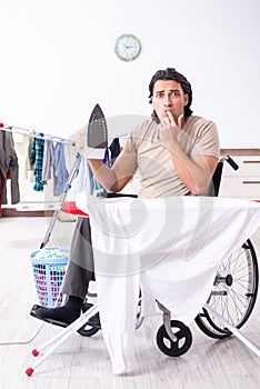 Young man in wheel-chair doing ironing at home