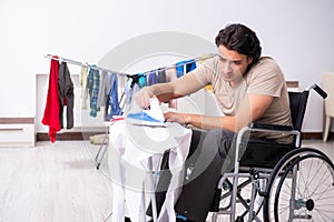 Young man in wheel-chair doing ironing at home